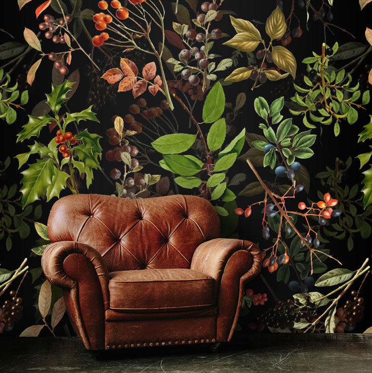 illustrated holly and green foliage on black background wall mural with brown leather armchair