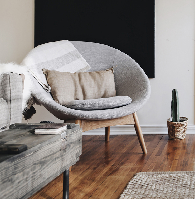 round styled grey chair with black canvas painting behind it