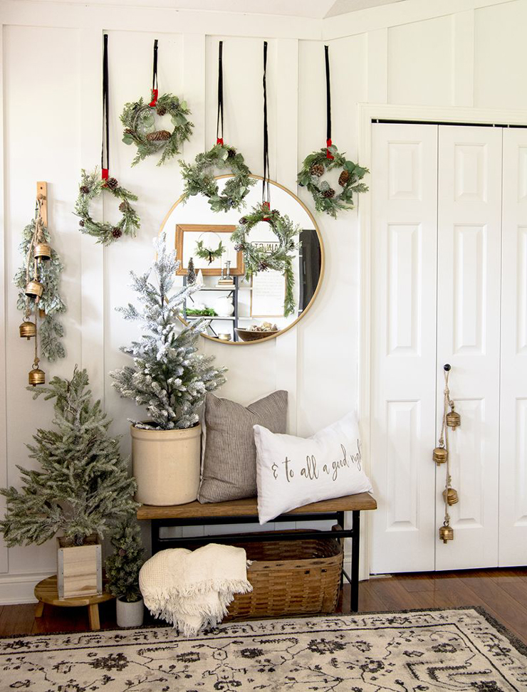 white Scandi hallway with wall wreath decorations, bells and Christmas trees