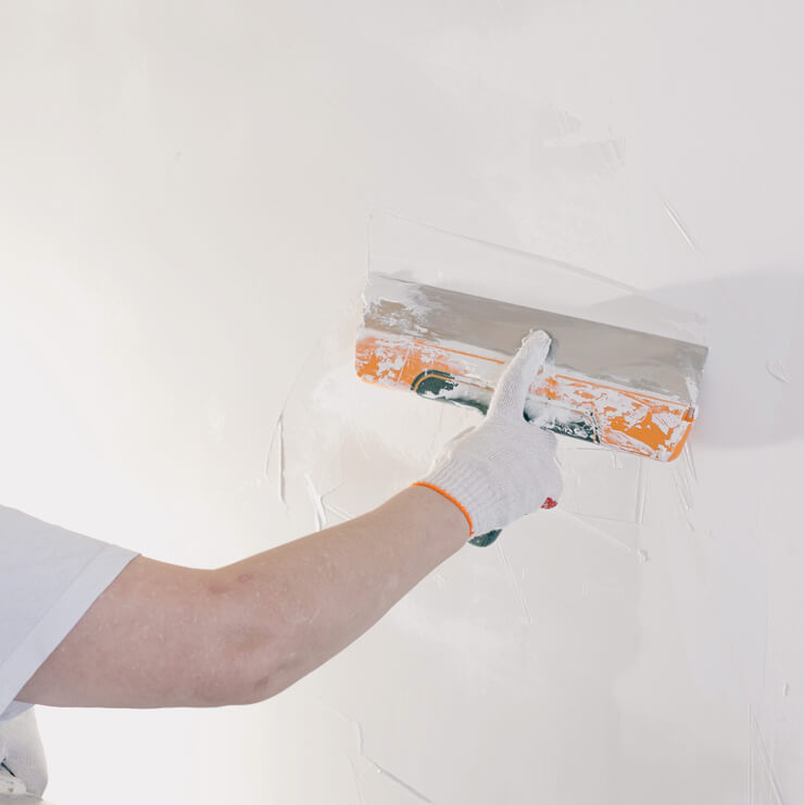 a glove hand plastering wall with white plaster