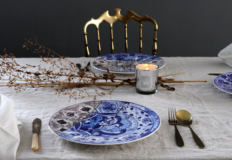 blue and white oriental plate fixed with gold lines on table with other plates, white table cloth and dried floral decoration centrepiece