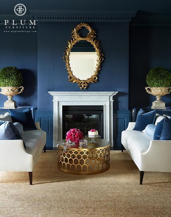 navy painted walled living room with white chairs and gold coffee table and mirror