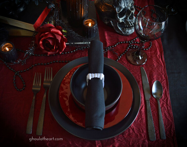 Red and black tableware with a black napkin held by white vampire teeth