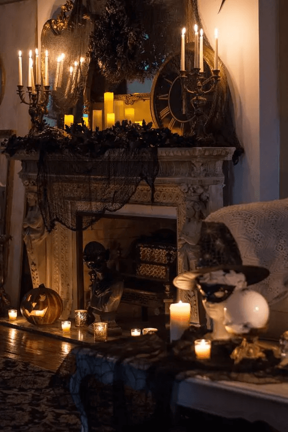 Dark fireplace decorated with black netting, candles and pumpkins