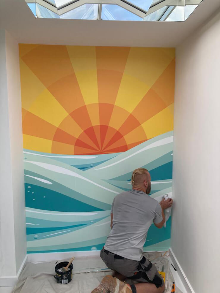 man installing wall mural