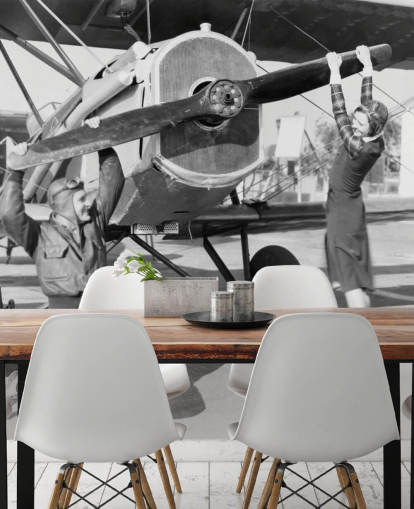 Casal brincando com uma hélice em um mural de avião 