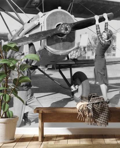 Casal brincando com uma hélice em um mural de avião 