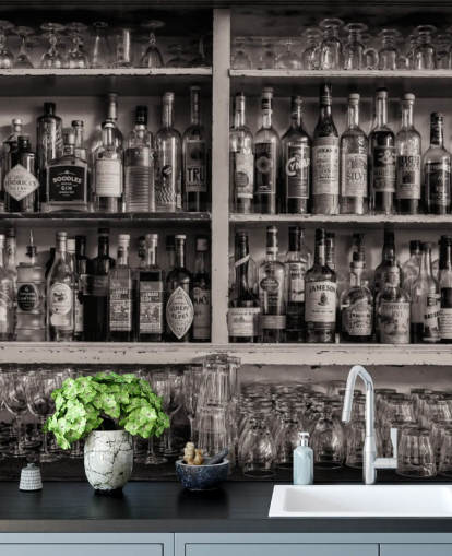 bouteilles en noir et blanc sur une étagère derrière un papier peint de bar