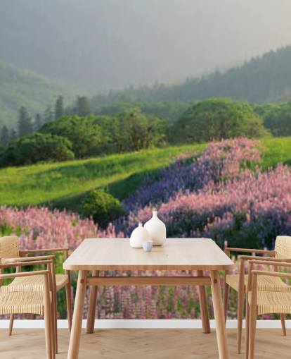 hellviolette und rosa Wildblumen im Feld mit grünen Hügeln Tapete
