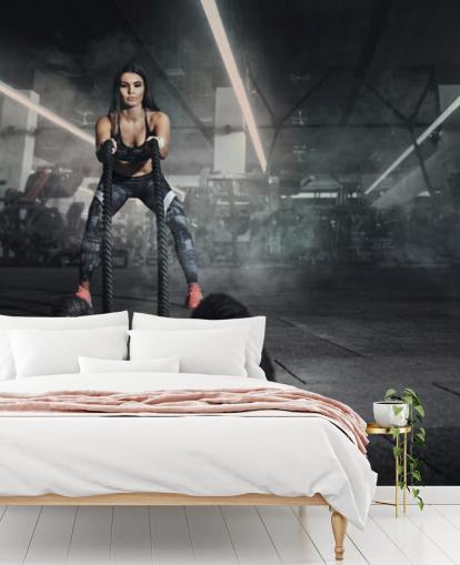 Powerful muscular woman fitness trainer do battle workout with ropes mural