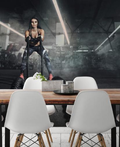 Powerful muscular woman fitness trainer do battle workout with ropes mural
