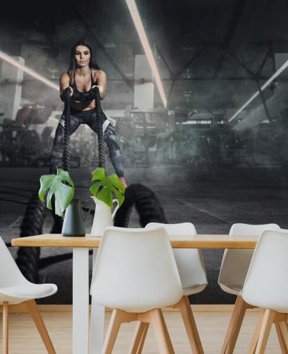 Powerful muscular woman fitness trainer do battle workout with ropes mural