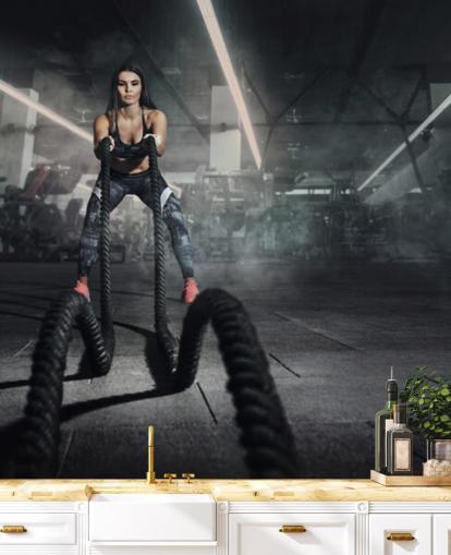 Powerful muscular woman fitness trainer do battle workout with ropes mural