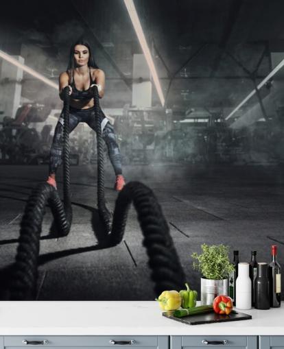 Kraftfull muskulös kvinna fitness tränare göra strid träning med rep väggmålning