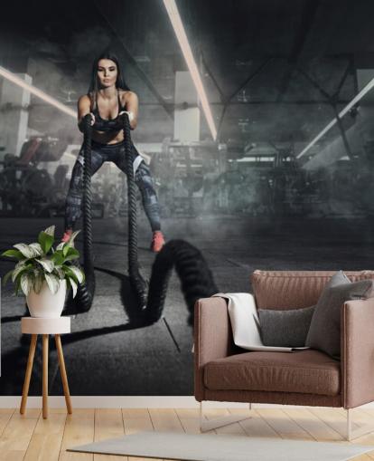 Powerful muscular woman fitness trainer do battle workout with ropes mural