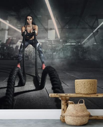 Kraftvolle muskulöse Fitnesstrainerin macht Kampftraining mit Seilen Wandbild