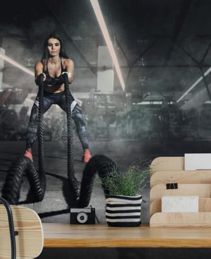 Potente allenatore di fitness donna muscolosa fa allenamento di battaglia con murale di corde