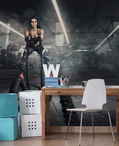 Powerful muscular woman fitness trainer do battle workout with ropes mural
