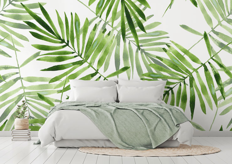 white and green leaf print wallpaper behind white bed