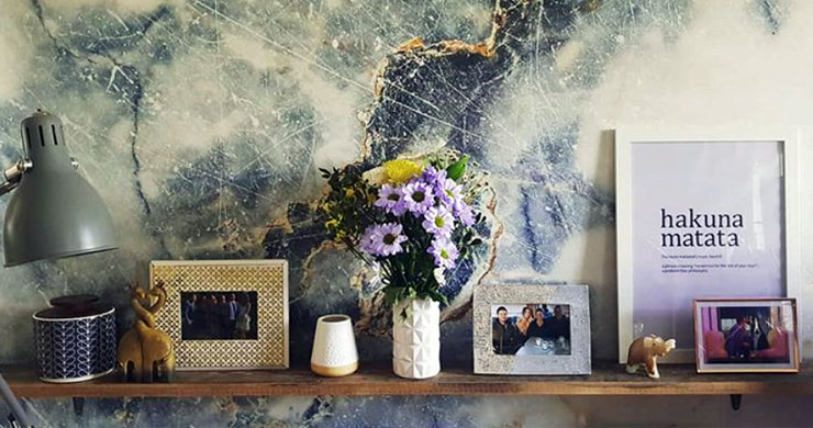 blue and white marble effect wallpaper behind shelf with flowers and ornaments on