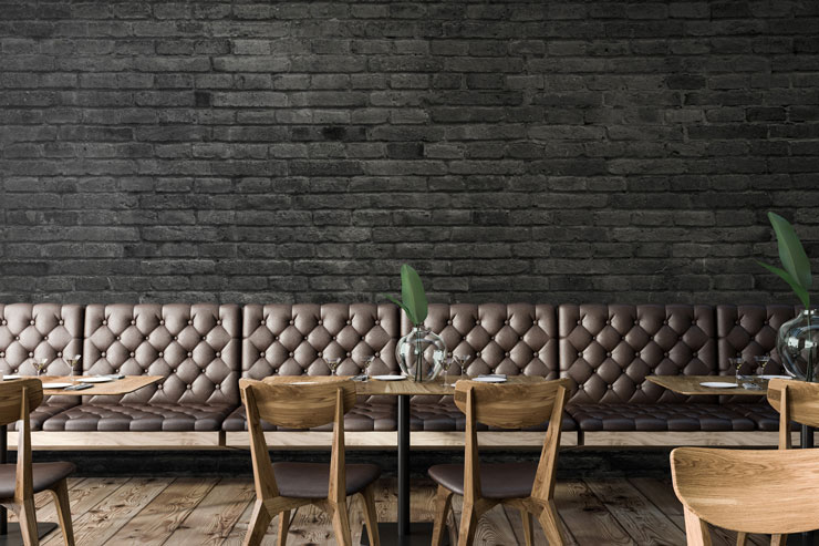 painted black bricks wallpaper in restaurant with leather studded chairs and wooden tables