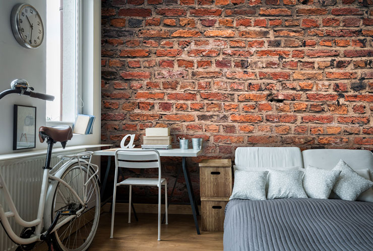 red brick wall in trendy grey and white bedroom