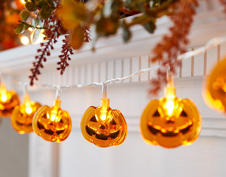 smiling orange pumpkin lights hanging from a fireplace