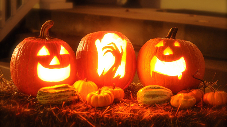 carved orange pumpkin lanterns on a hay bale