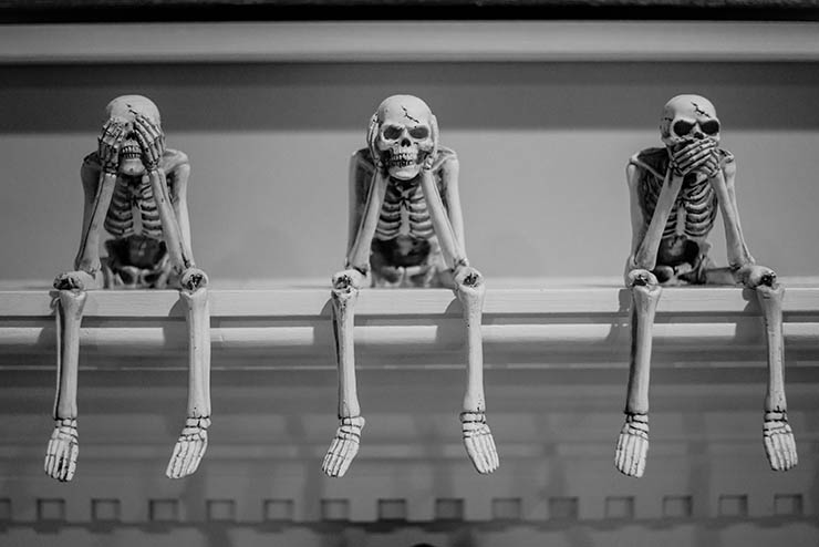 three mini skeletons hanging from a mantel (great Halloween decor ideas)