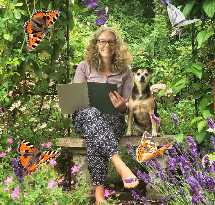 female artist sat in English garden drawing with her small dog sat next to her