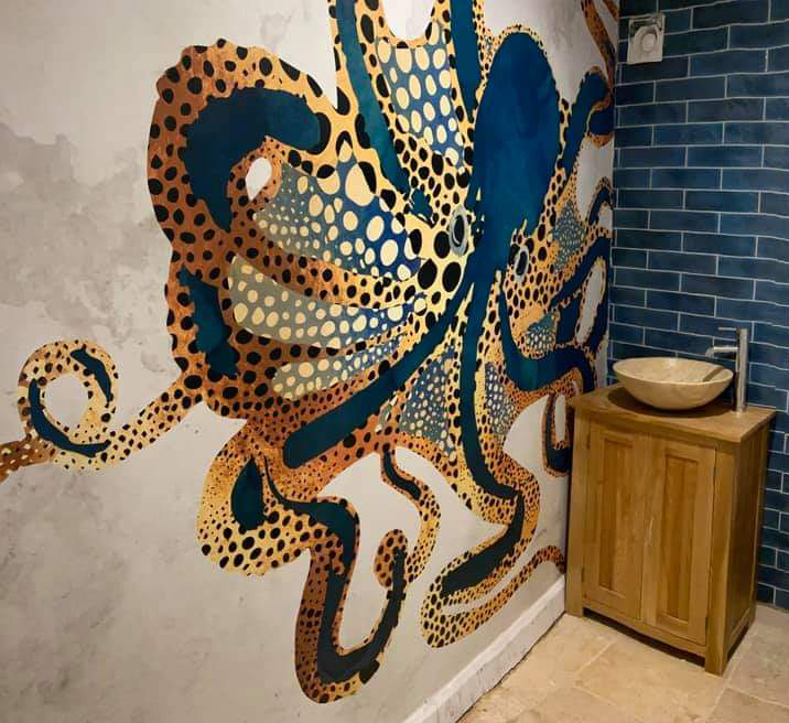 inky-blue and gold colour art deco octopus wall mural in bathroom with blue tiles to match