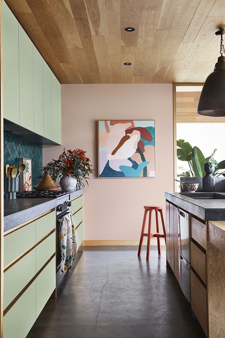 peach-pink walls in kitchen with green cabinets and abstract art work on walls