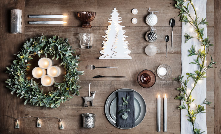rustic wooden table with mistletoe wreath and simple scandi christmas dinner set