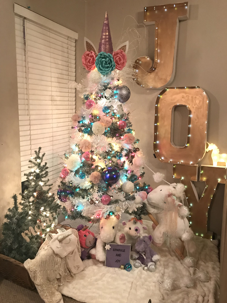 christmas tree covered and surrounded by white and pink unicorn decorations