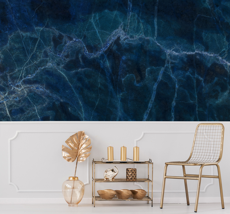 inky blue marble wall mural above white panelling in lounge with gold decor