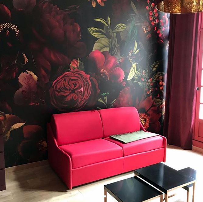 dark maroon floral wallpaper in lounge with pink sofa
