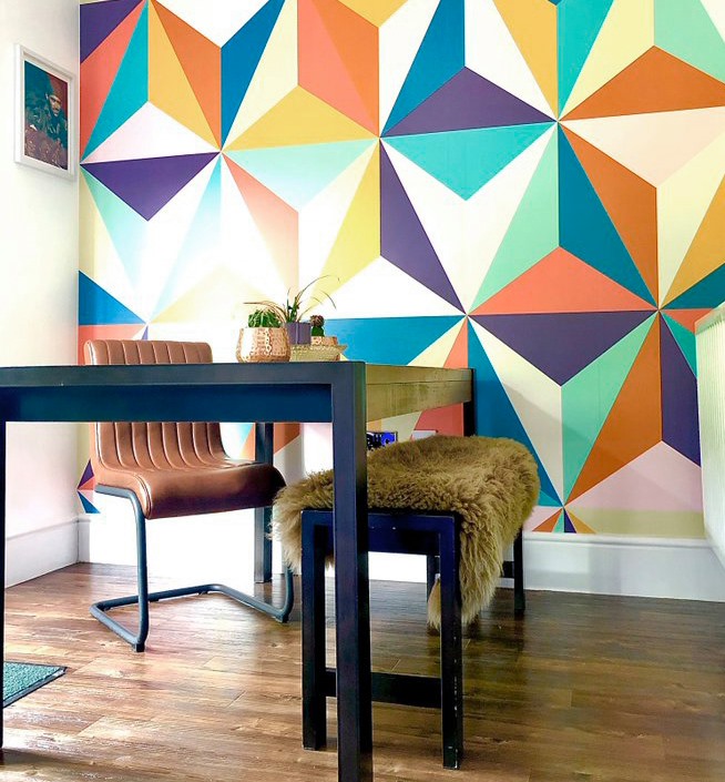 colourful retro geometric wallpaper in '70s style room with wooden table and brown leather chair