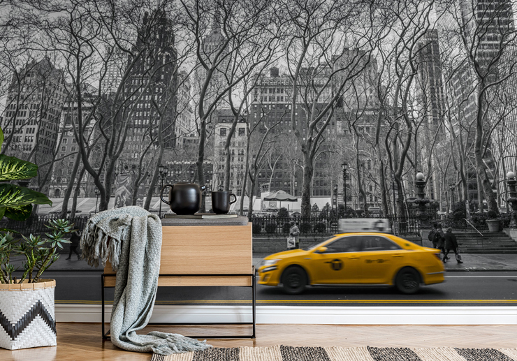 black and white photo of new york central park railing with yellow cab wallpaper in room with small table and blanket