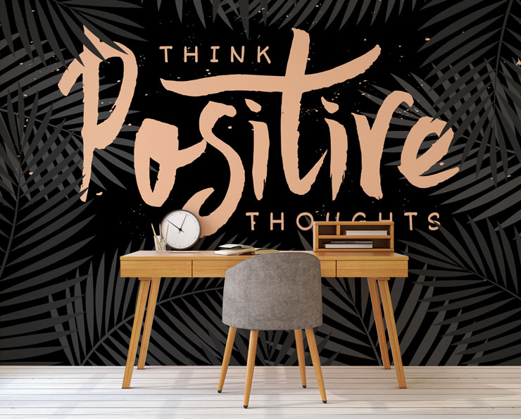 black wallpaper with pink writing that says 'think positive thoughts' in home office with wooden desk and grey chair