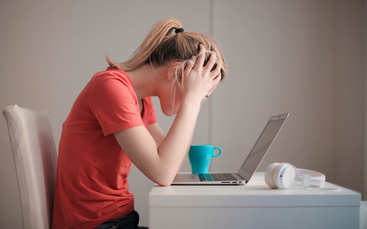 woman with blond hair and red t shirt sat at desk stressed