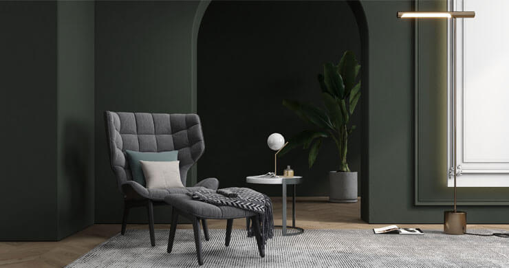 living room with dark green and black walls and grey armchair and carpet
