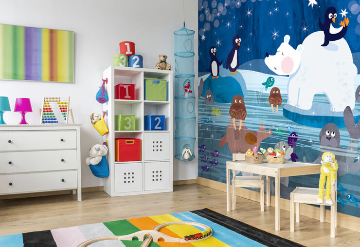 polar bear, penguins, walrus and seal illustration mural in child's bedroom with play mat, drawers and a drawing table