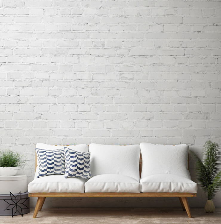 white brick effect wallpaper in minimalist lounge with white sofa and blue cushions