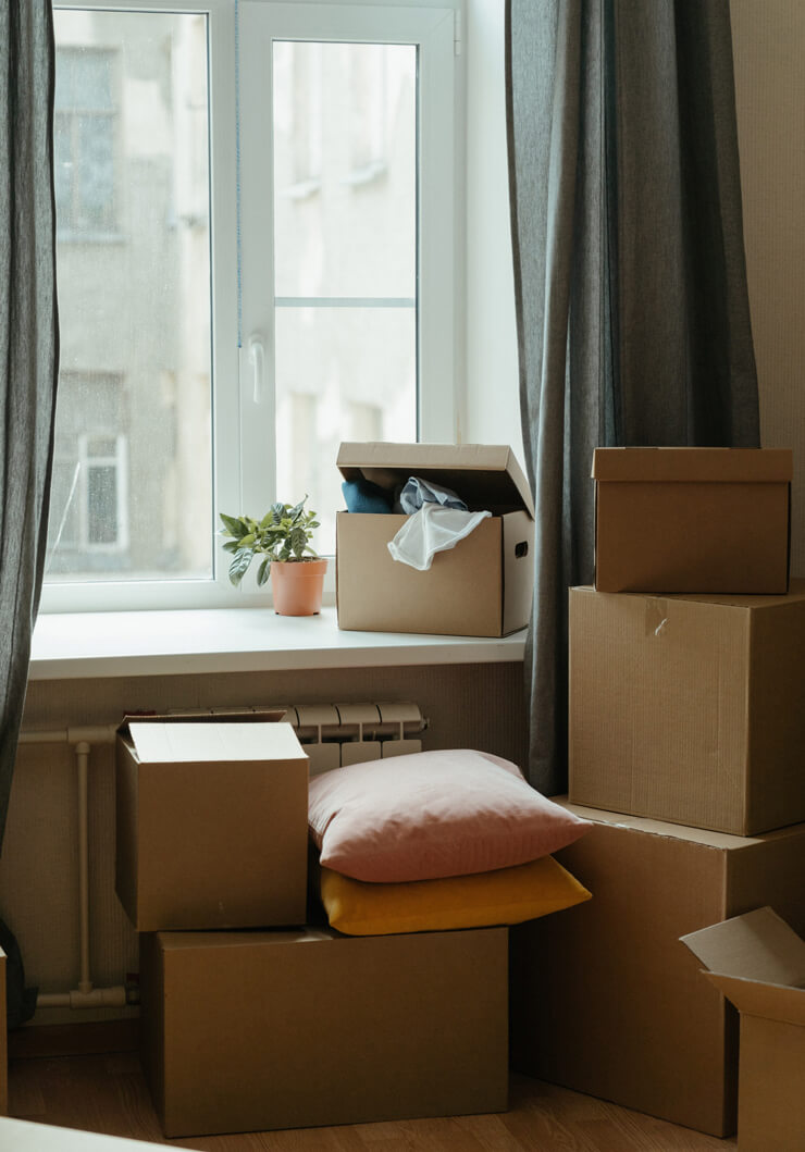 pile of cardboard moving boxes next to a window