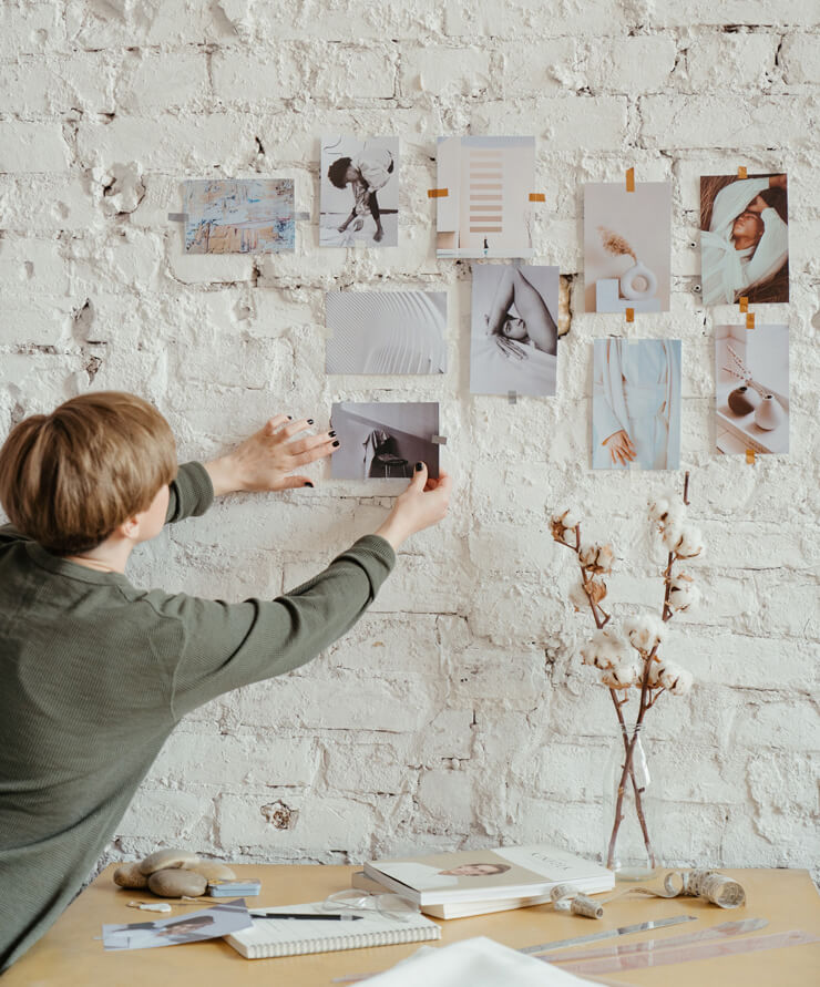 short haired woman changing photographs on her wall