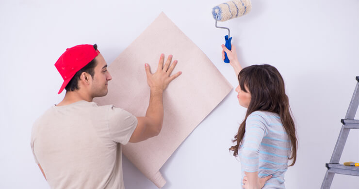 man and woman with wallpaper and paste roller