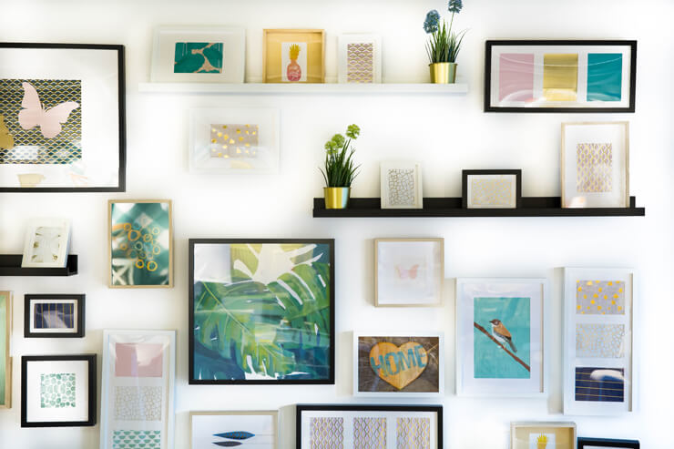 pastel pink, yellow and blue prints framed on wall in black and white frames
