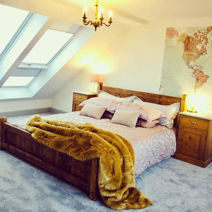 pink bed with brown faux fur rug on it with map mural on wall in bedroom