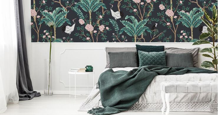 dark oriental wallpaper with birds, palm trees and roses in it in a decadent bedroom with dark green bedding