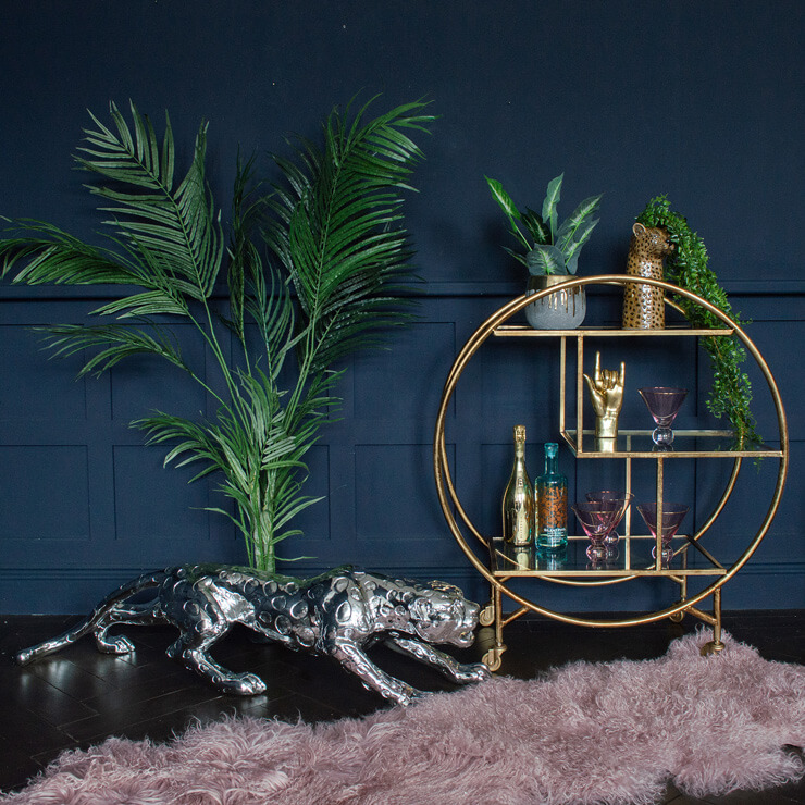 monochrome jaguar ornament, round golden floor shelf and tropical plant in navy room
